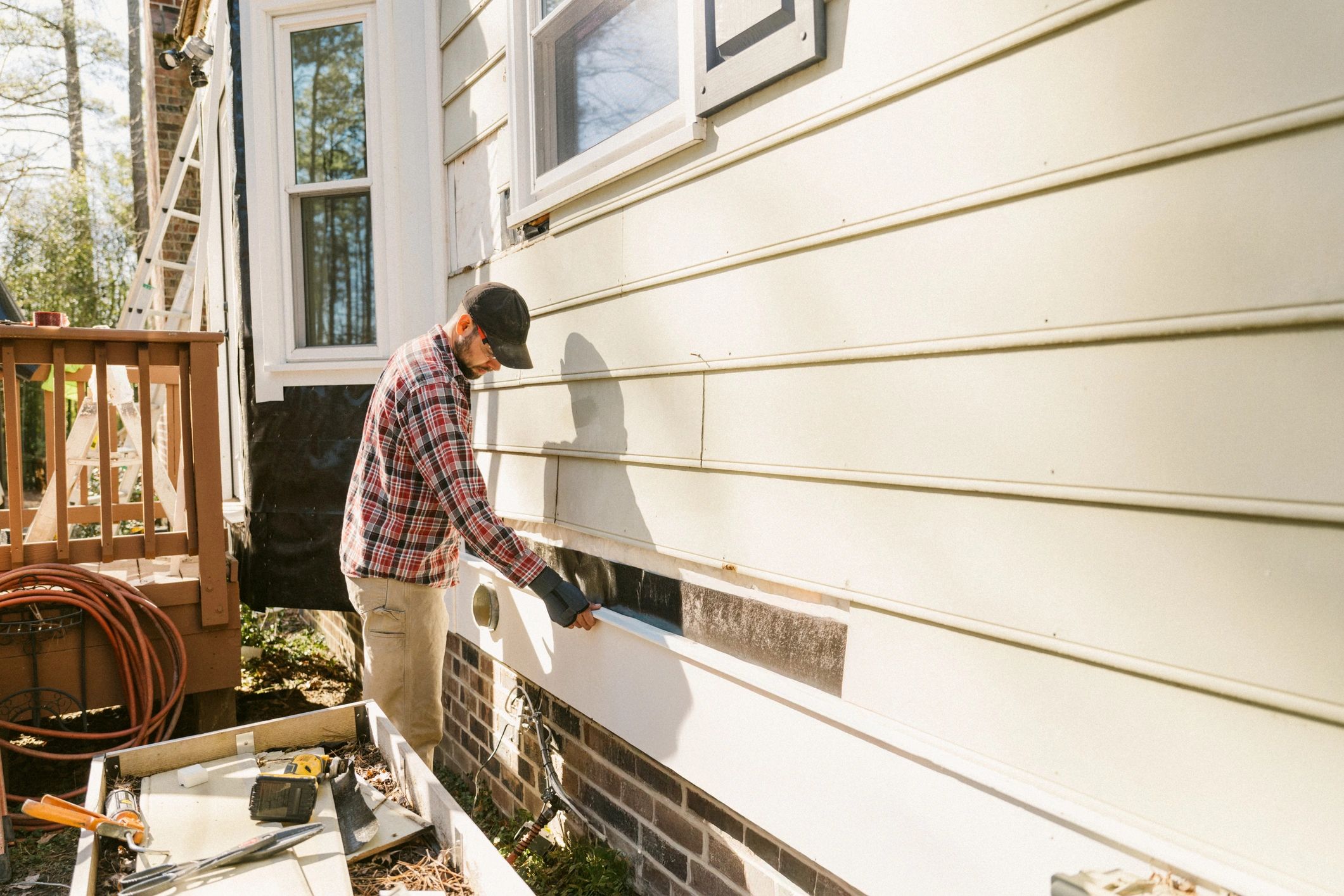 Wildlife exclusion technician sealing exterior entry points on a residential home
