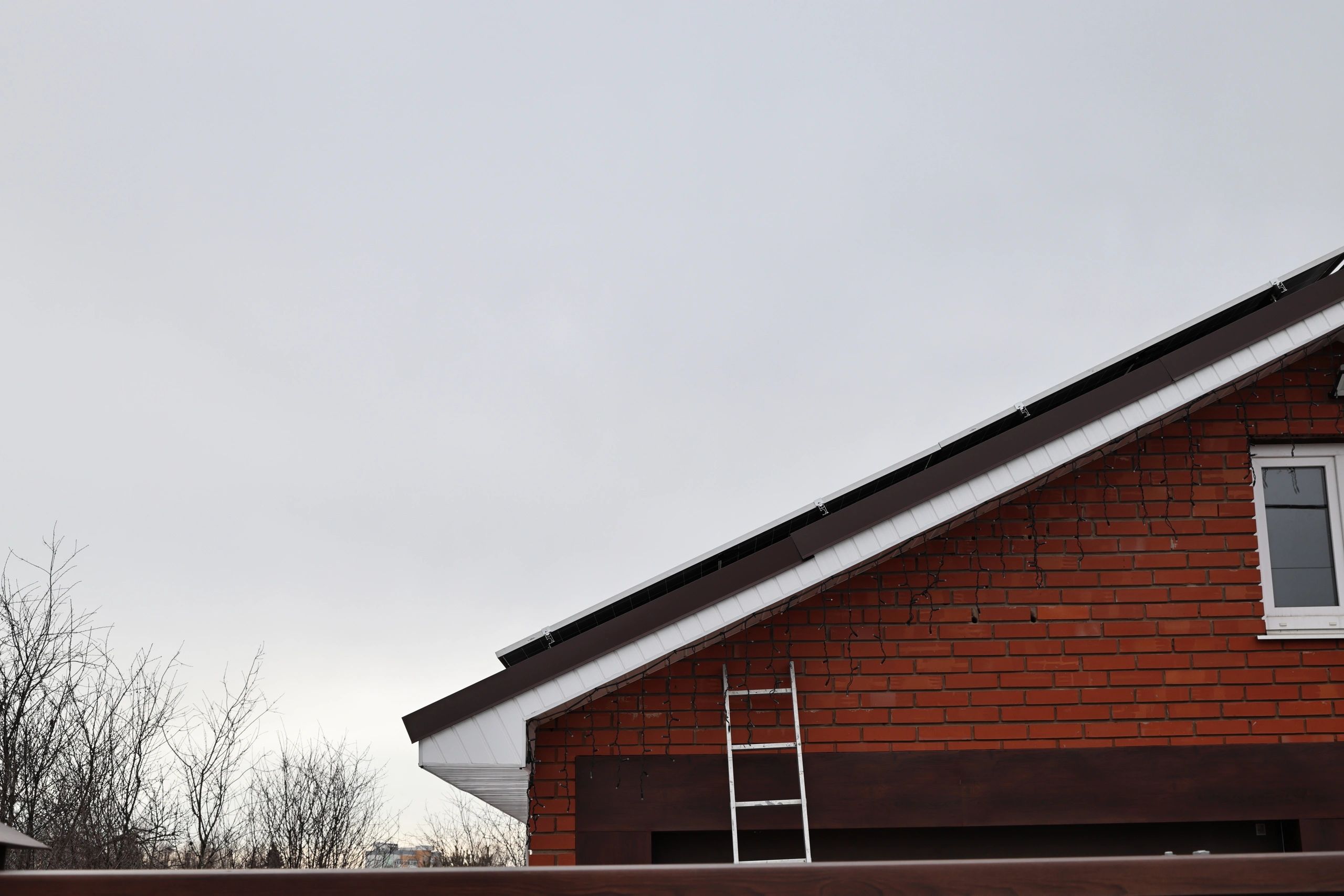 Ladder positioned at residential roofline for exterior inspection